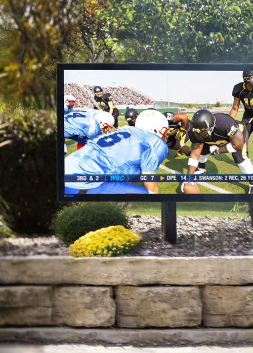 An outdoor TV displaying a football game.