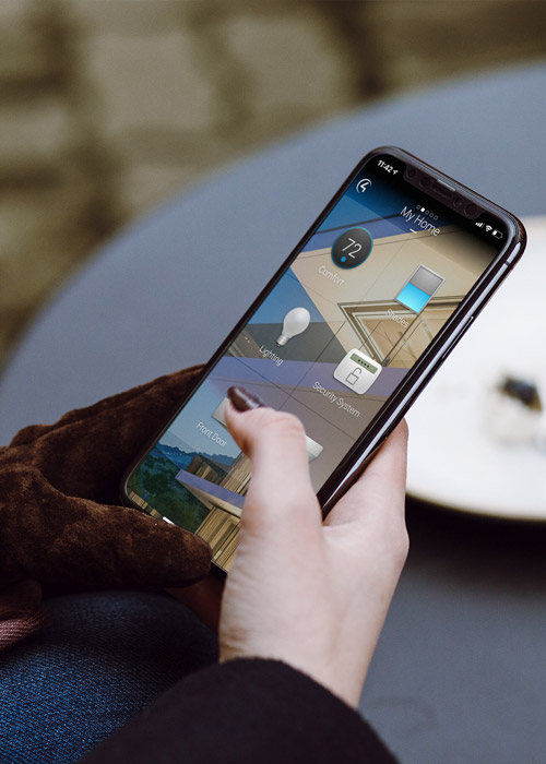 Hand holding a smartphone with a Control4 interface on screen.