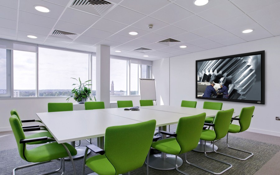 A conference room with a large display and green chairs.