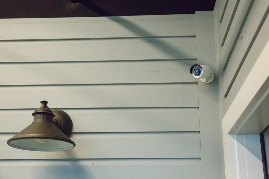 An outdoor security camera mounted high over the entryway of a home.