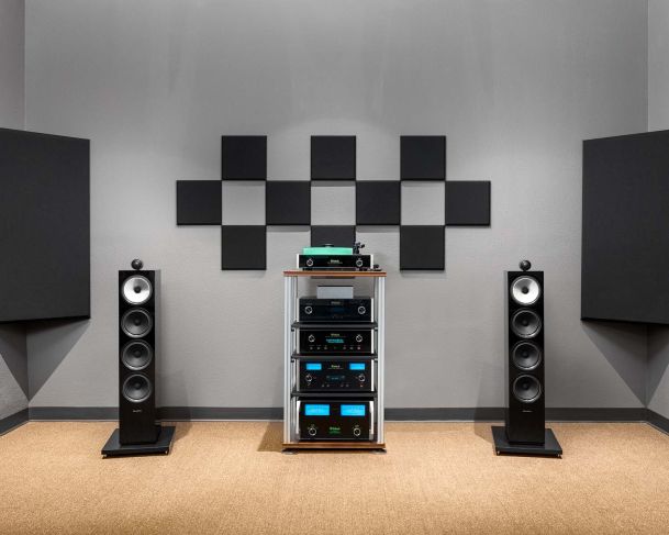 Modern audio setup with black floor speakers and stacked amplifiers