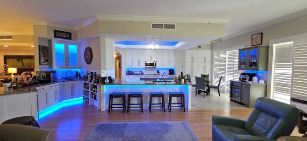 Modern open kitchen with blue LED accent lighting and bar seating