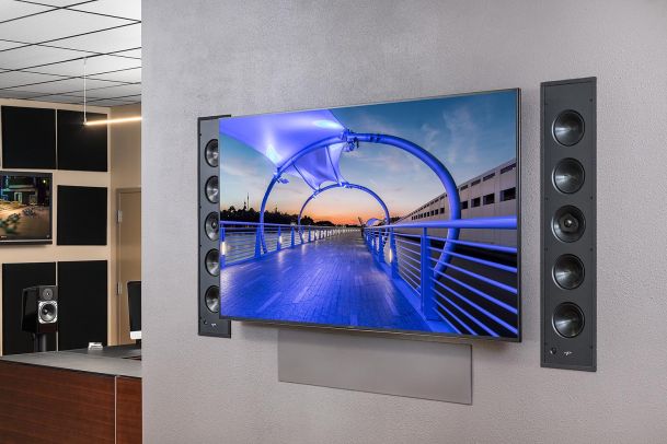 Wall-mounted TV with built-in speakers on each side displaying modern bridge scene