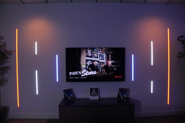 TV display with colored LED wall accents showing Netflix Pawn Stars